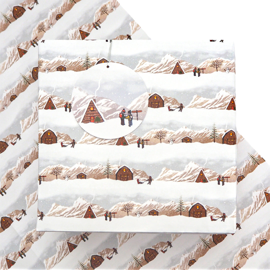 Present wrapped in bright stem Christmas wrapping paper and tag with a repeated Illustration of a Winter Landscape with kids playing in the snow.