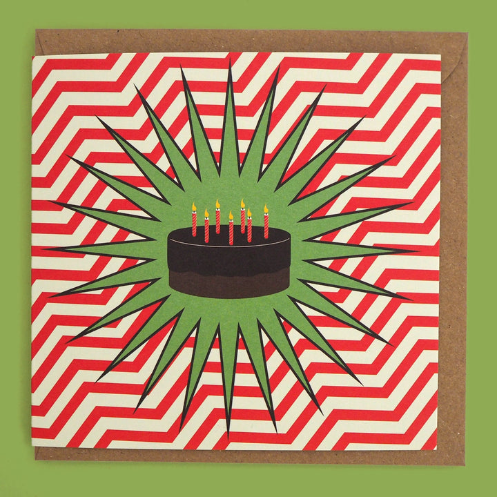 Birthday Card with illustration of a chocolate cake and candles in the style of a comic book or POP Art  design on a red and white zigzag pattern, with a brown Kraft envelope.