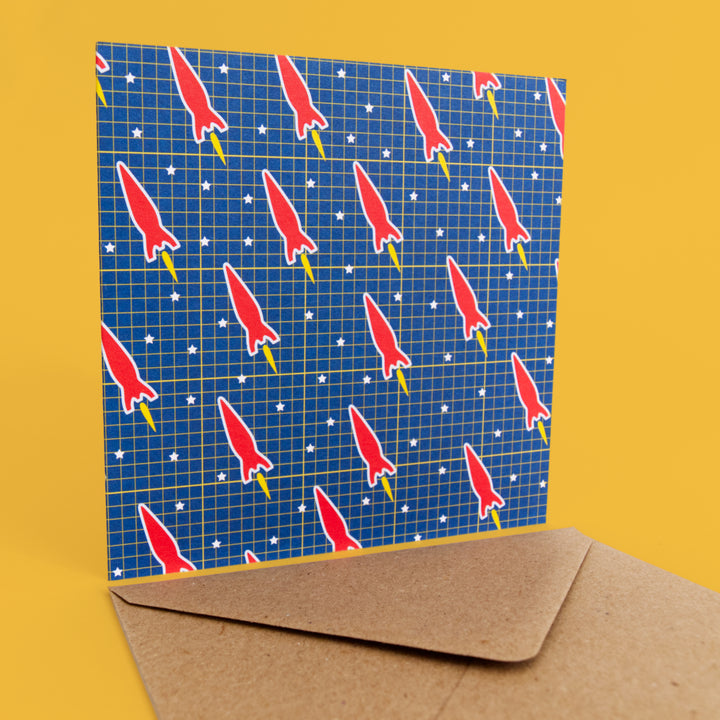 Bright Stem Greeting card with sci-fi red space rocket pattern on blue background with brown envelope. Suitable for kids birthday card. Stud upright with envelope bellow