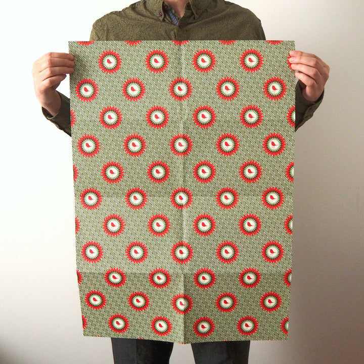 Bright Stem Recyclable Christmas Wrapping Paper Gift Wrap Folded. shot of robin illustration on green zigzag pattern. Held by Artist and Designer. 