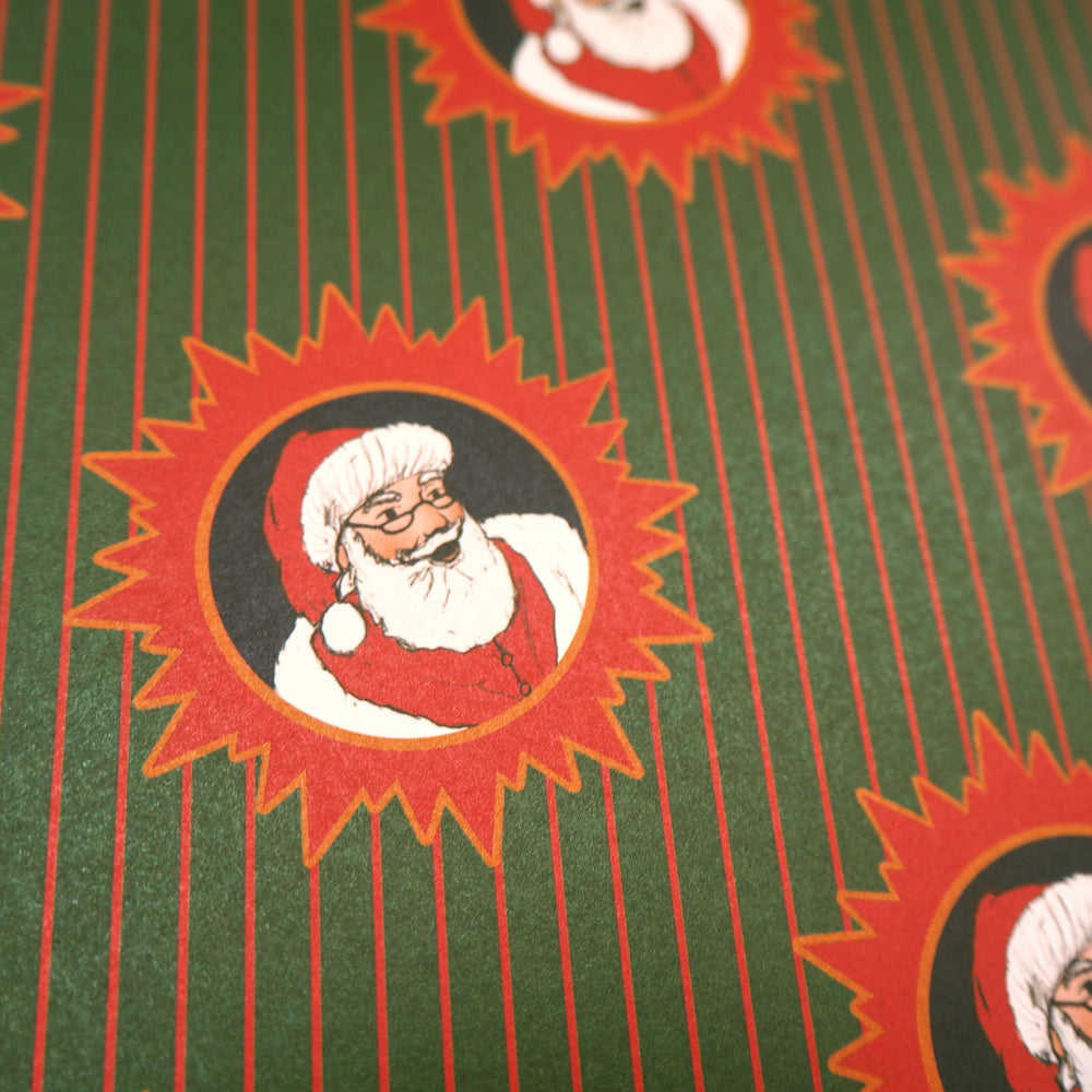 Close up of wrapping paper pattern with Santa Claus design on a green and red stripped background