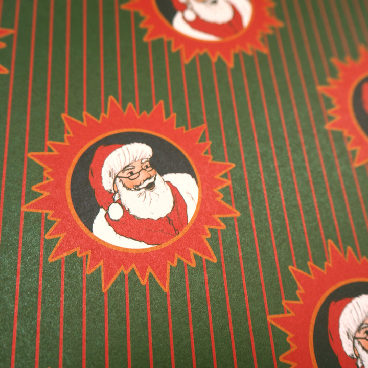 Close up of wrapping paper pattern with Santa Claus design on a green and red stripped background