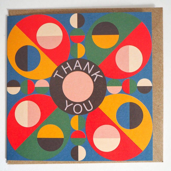 Express your gratitude with these striking modern thank you cards featuring bold geometric designs from Bright Stem. Sold by the Artist. Each set includes 12 cards with three unique patterns (4 of each design) accompanied by matching recycled brown paper envelopes. The vibrant colour palette combines rich reds, blues, greens, and yellows in an eye-catching circular motif, with each design centred around a distinctive 'Thank You' message. Measuring 12 x 12 cm