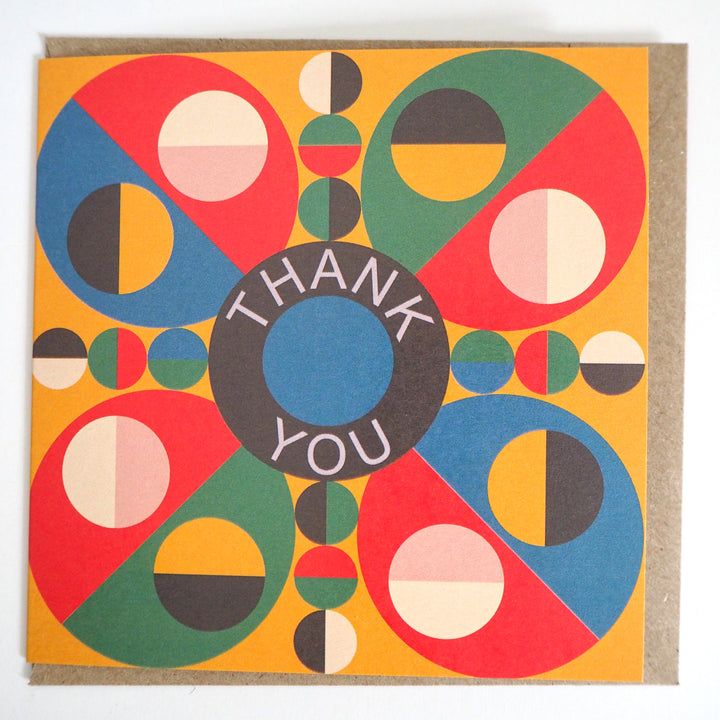 Express your gratitude with these striking modern thank you cards featuring bold geometric designs from Bright Stem. Sold by the Artist. Each set includes 12 cards with three unique patterns (4 of each design) accompanied by matching recycled brown paper envelopes. The vibrant colour palette combines rich reds, blues, greens, and yellows in an eye-catching circular motif, with each design centred around a distinctive 'Thank You' message. Measuring 12 x 12 cm