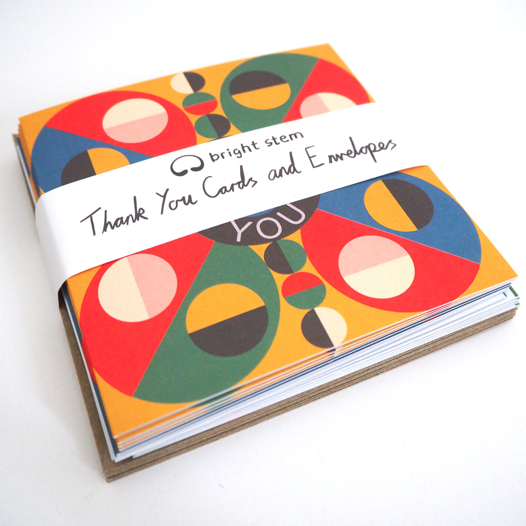 Express your gratitude with these striking modern thank you cards featuring bold geometric designs. Sold by the Artist. Each set includes 12 cards with three unique patterns (4 of each design) accompanied by matching recycled brown paper envelopes. The vibrant colour palette combines rich reds, blues, greens, and yellows in an eye-catching circular motif, with each design centred around a distinctive 'Thank You' message. Measuring 12 x 12 cm, these cards are crafted from high-quality recycled card