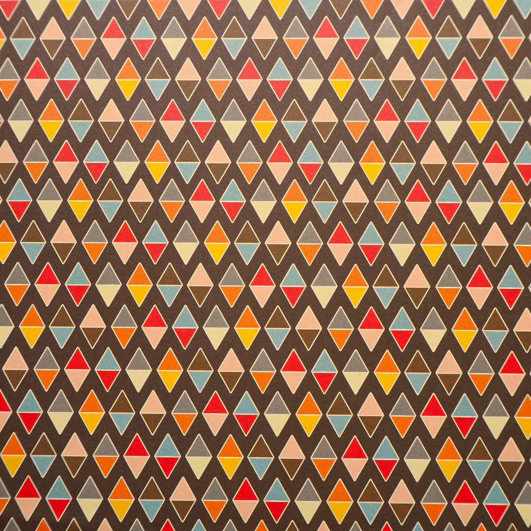 Bright Stem recyclable wrapping paper. Geometric diamond pattern made of multicoloured triangles on a chocolate brown background. Close up


