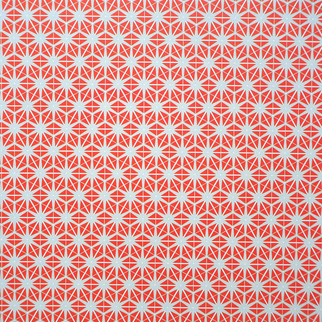 Bright Stem recyclable wrapping paper. Geometric star pattern made of orange triangles on a grey background. Close up
