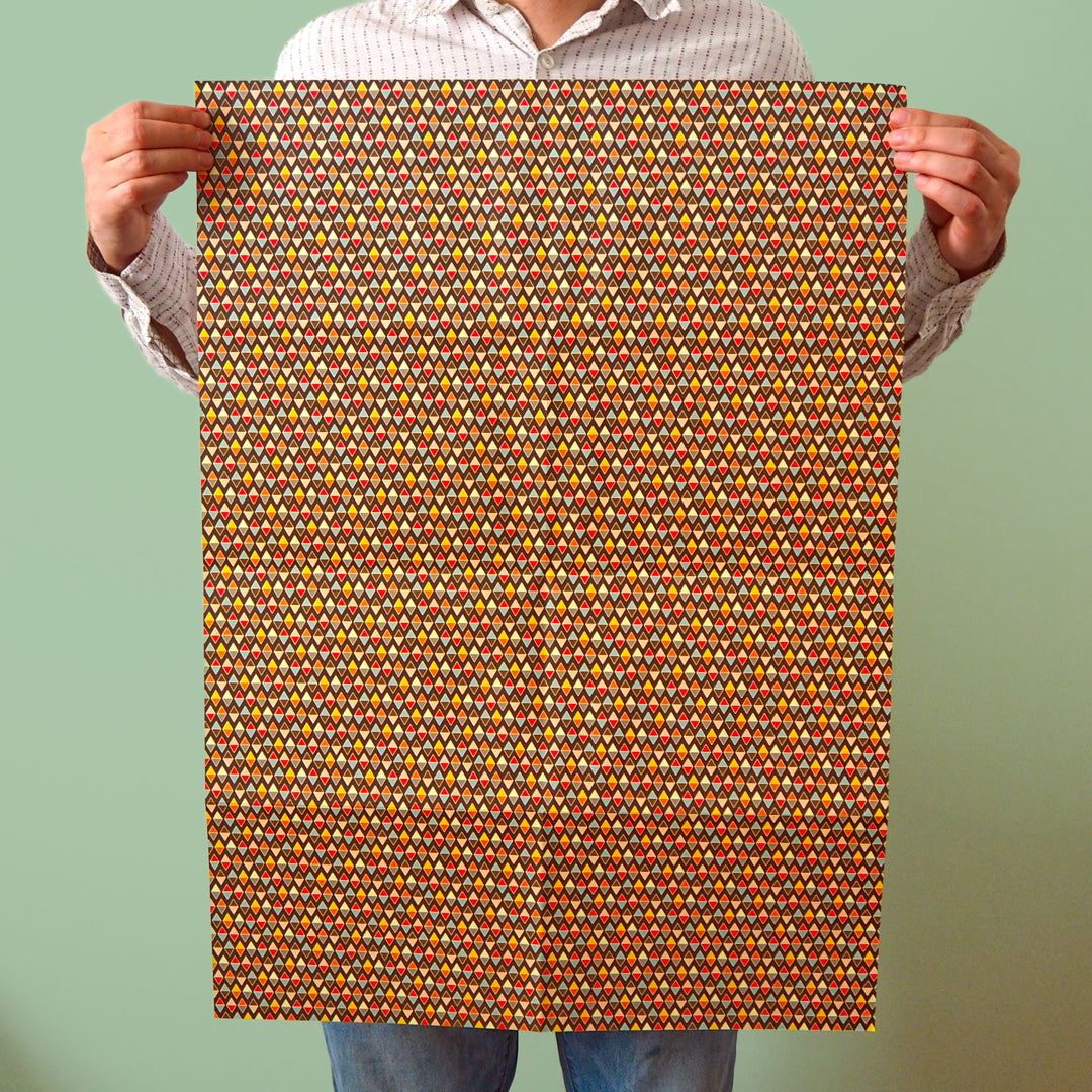Bright Stem recyclable wrapping paper sheet held by artist/designer. Multicoloured diamond pattern on chocolate brown. 50x70cm