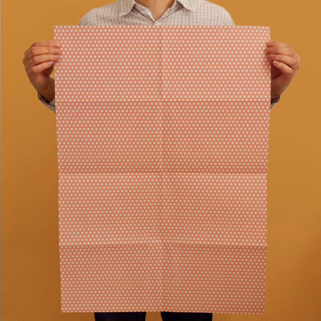 Bright Stem recyclable wrapping paper sheet held by artist/designer. orange/red and grey star pattern. 50x70cm