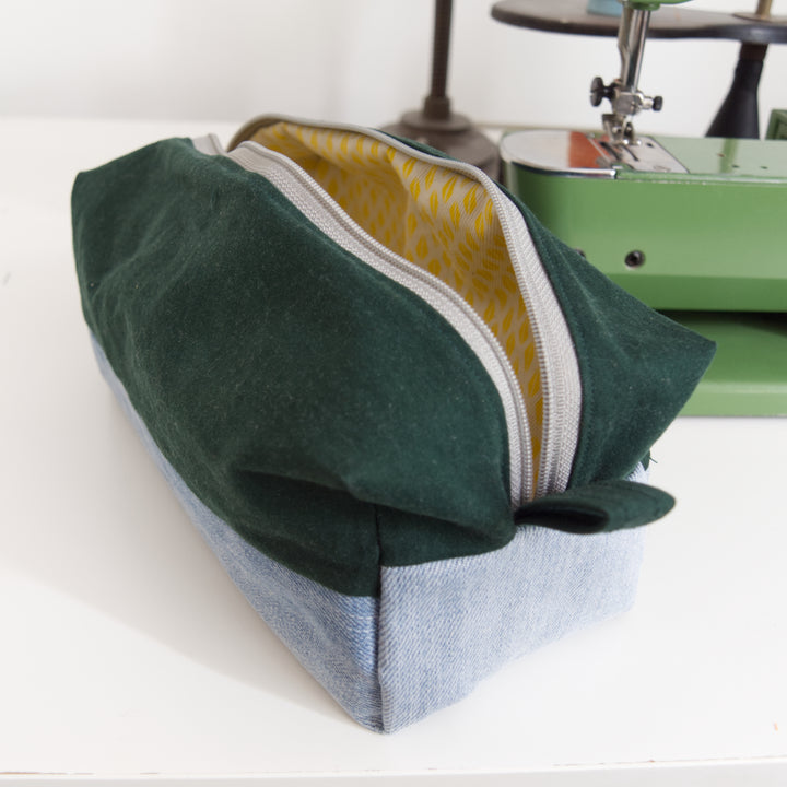 Bright Stem wash bag made from green cotton and light blue denim upcycled fabric with a yellow and white cotton inner lining with grey zipper. Next to a vintage sewing machine.
