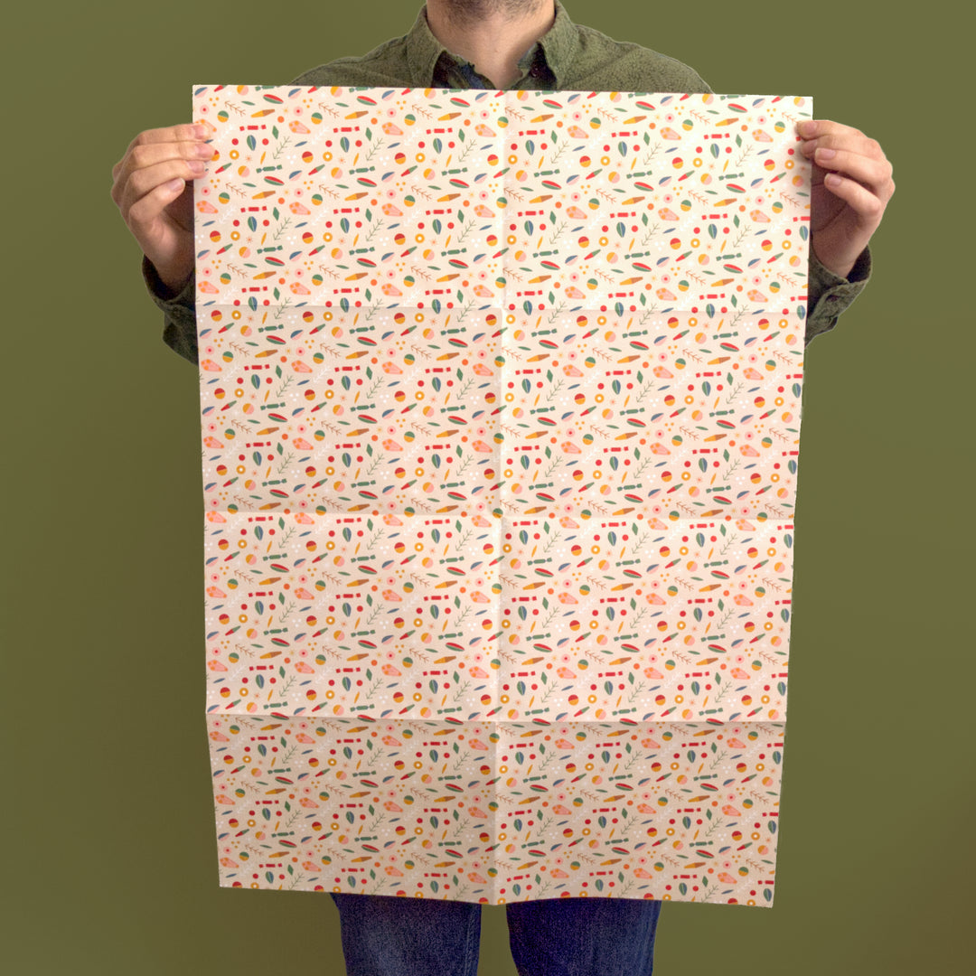 Artist/Designer holding a sheet of recyclable Christmas wrapping paper with a colourful pattern against a green background
