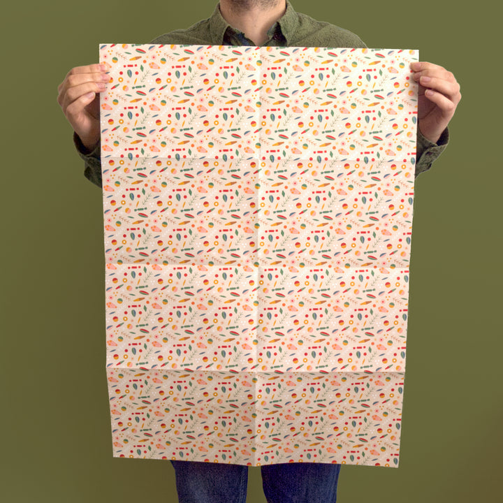 Artist/Designer holding a sheet of recyclable Christmas wrapping paper with a colourful pattern against a green background