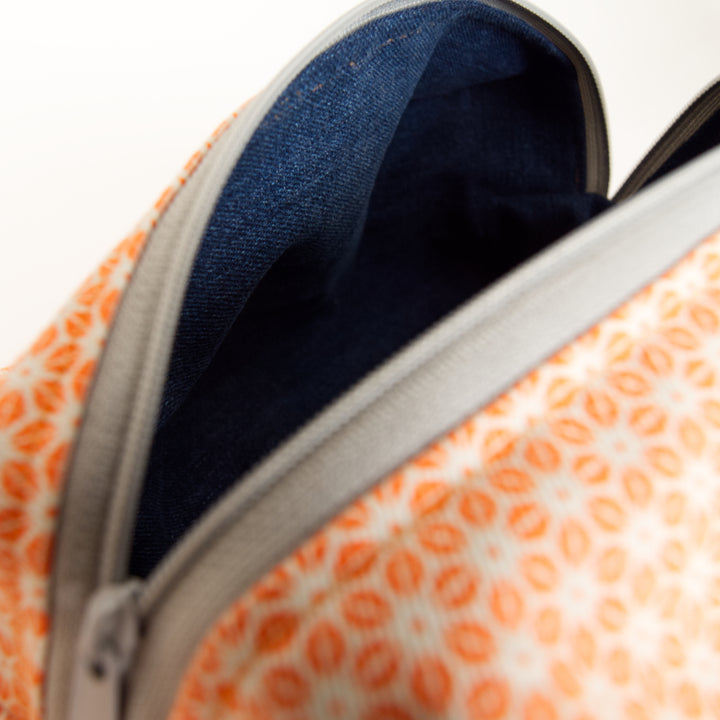 Close-up of Bright Stem  patterned wash bag with orange star patterns on exterior and dark blue denim interior.