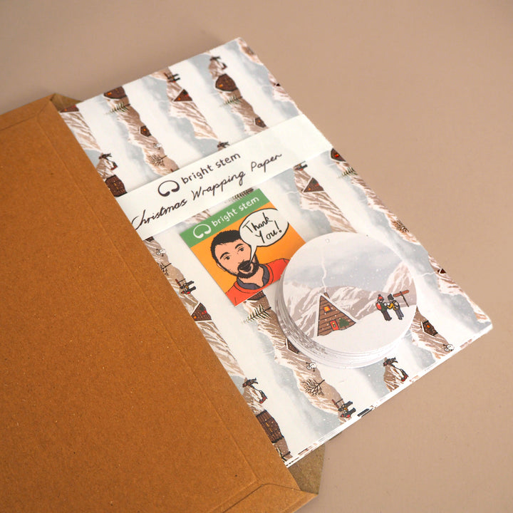 Bright Stem recyclable Christmas wrapping paper and tags with Winter landscape Illustration being packed in brown card folder