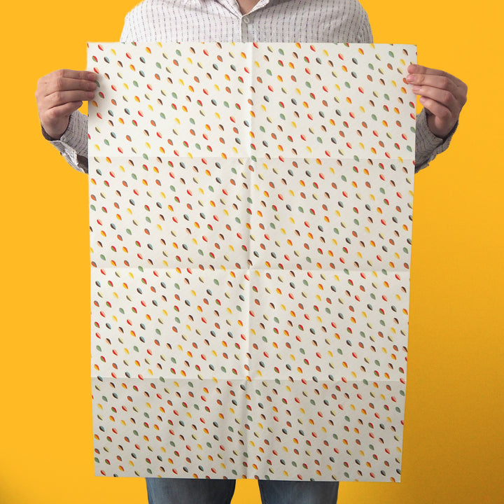 Bright Stem recyclable wrapping paper sheet held by artist/designer. Multicoloured abstract egg/leaf pattern on white. 50x70cm made in the UK