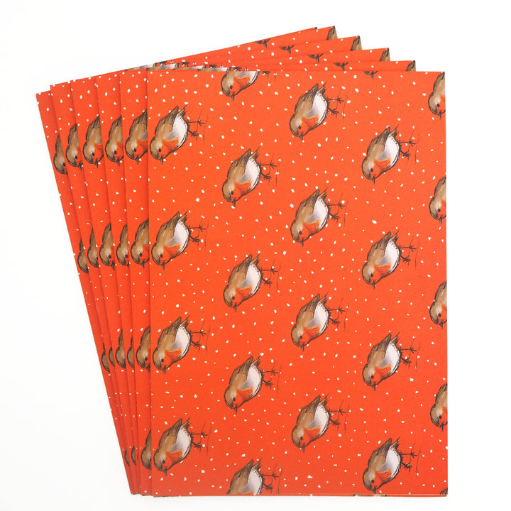 Stack of 6 folded sheets of orange recyclable Christmas wrapping paper with robin illustration printed on. From Bright Stem