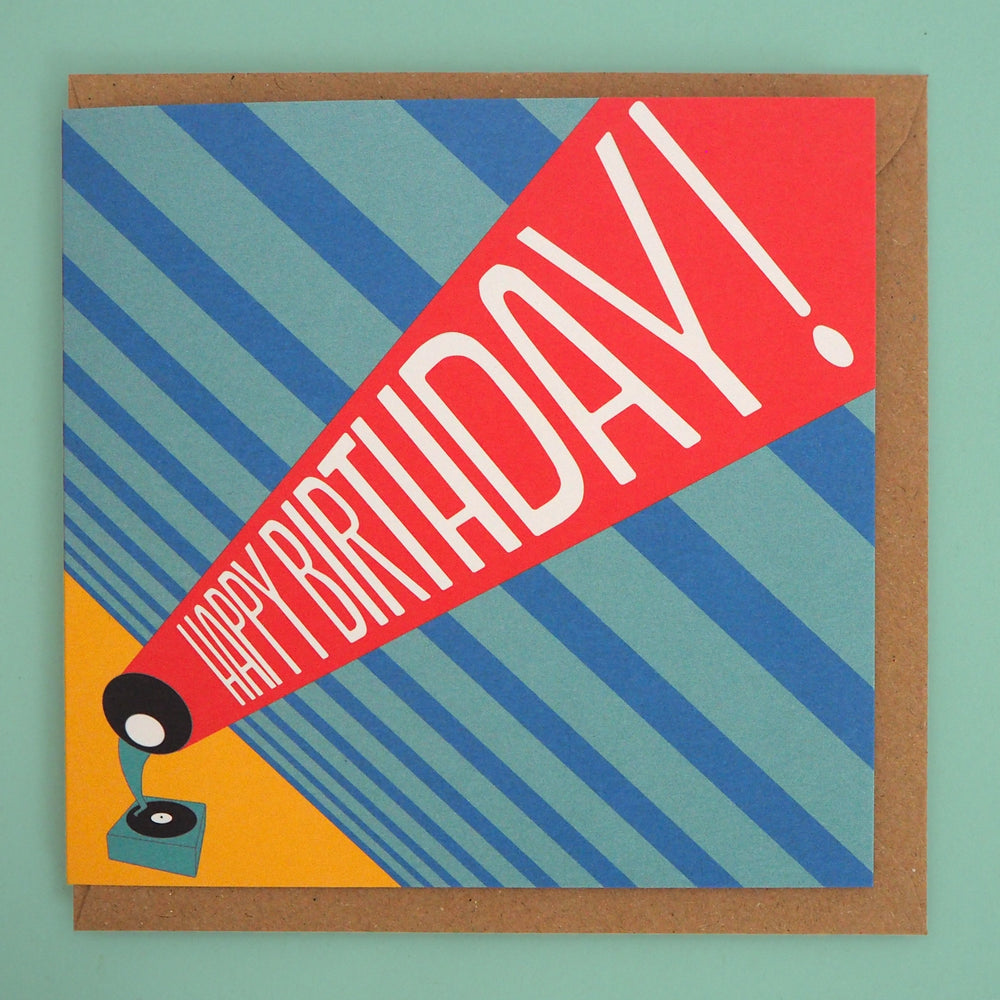 Colourful birthday card with 'Happy Birthday!' text and a record player graphic, accompanied by a brown envelope on a green background. Inspired by the Bauhaus graphic design 