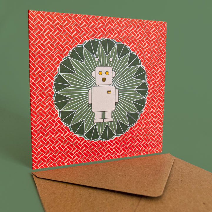 bright stem children's sc-fi birthday card. Ray the robot illustration on emerald green diamond shape with orangey red and white zigzag pattern. Stud up with brown craft envelope on a green background