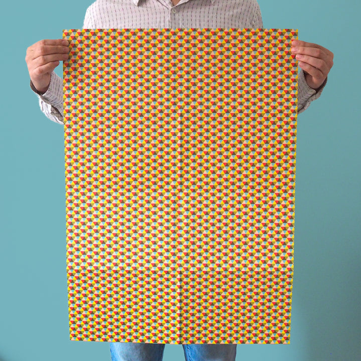 bright stem recyclable wrapping paper sheet held by artist/designer. Multicoloured geometric triangular pattern. 50x70cm