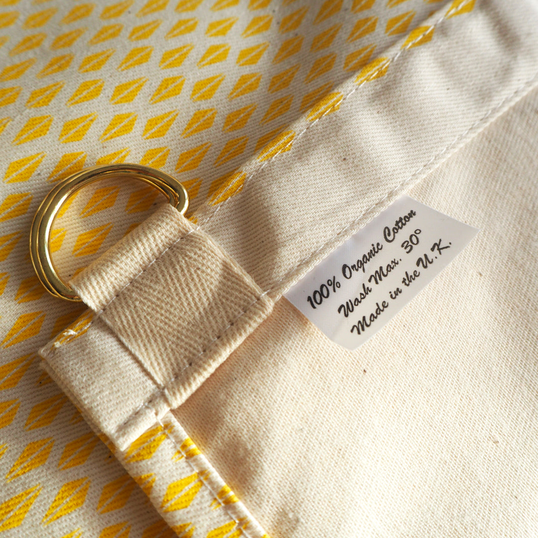 Bright Stem apron close up detail image of Yellow Triangle Pattern and reverse of fabric with d ring fastening to attach to strap.