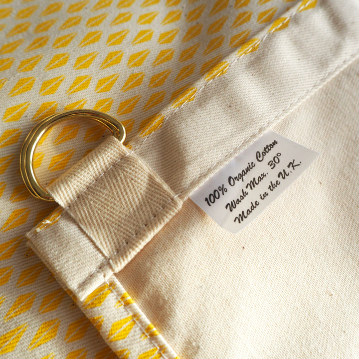 Bright Stem apron close up detail image of Yellow Triangle Pattern and reverse of fabric with d ring fastening to attach to strap.